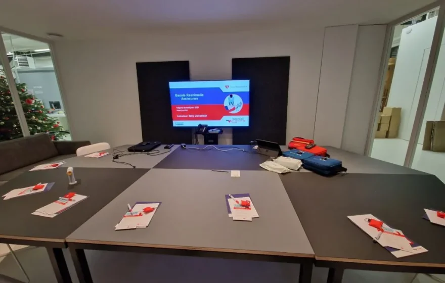 Cursusruimte met stoelen in een kring en reanimatiepoppen op de vloer